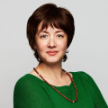 Portrait of a woman with short red hair, wearing a green shirt and bead necklace