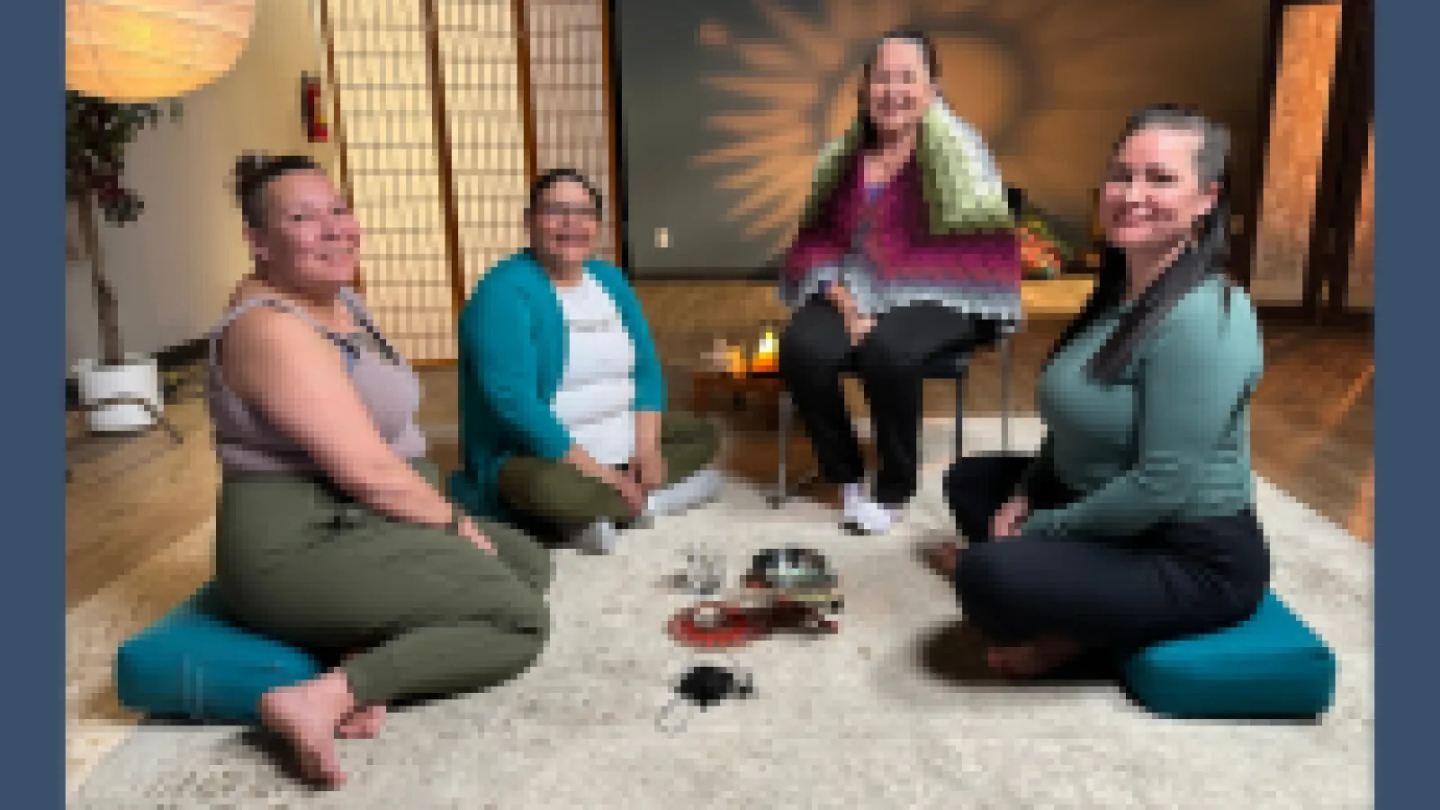 Four women sit on the floor smiling at the camera