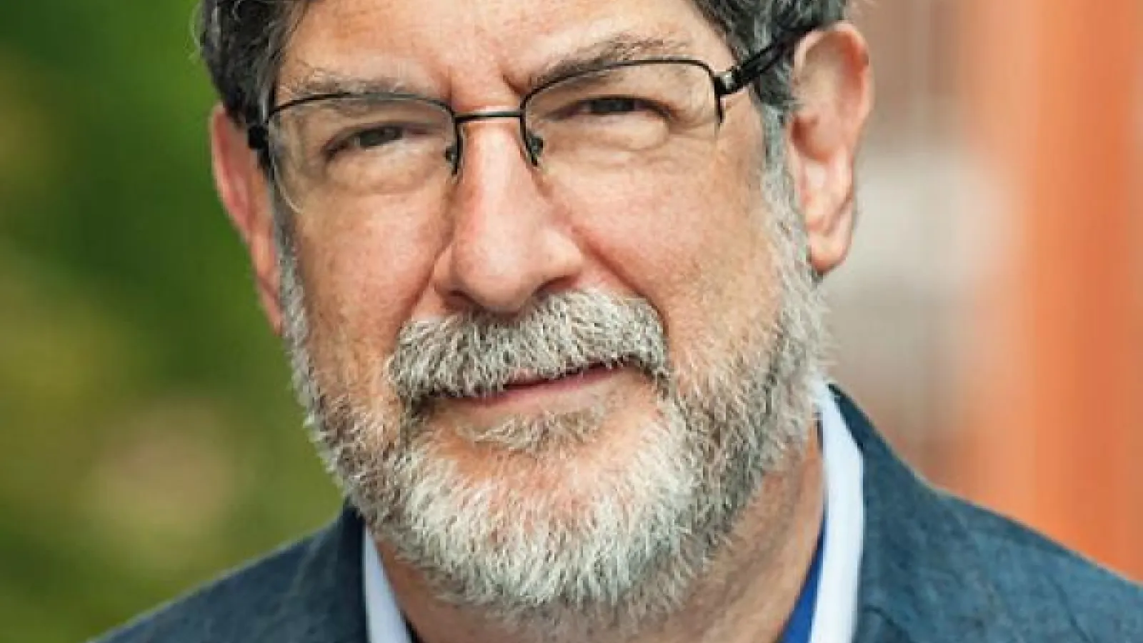 A person with a grey beard and glasses 