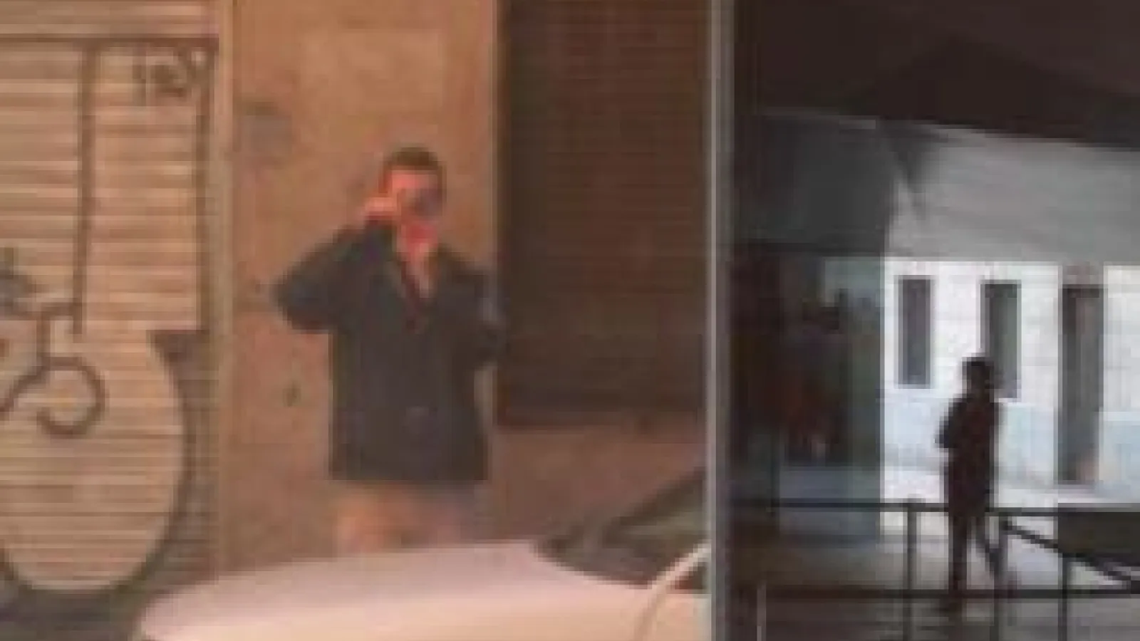 blurry photograph of a man standing behind a white car looking through a lens