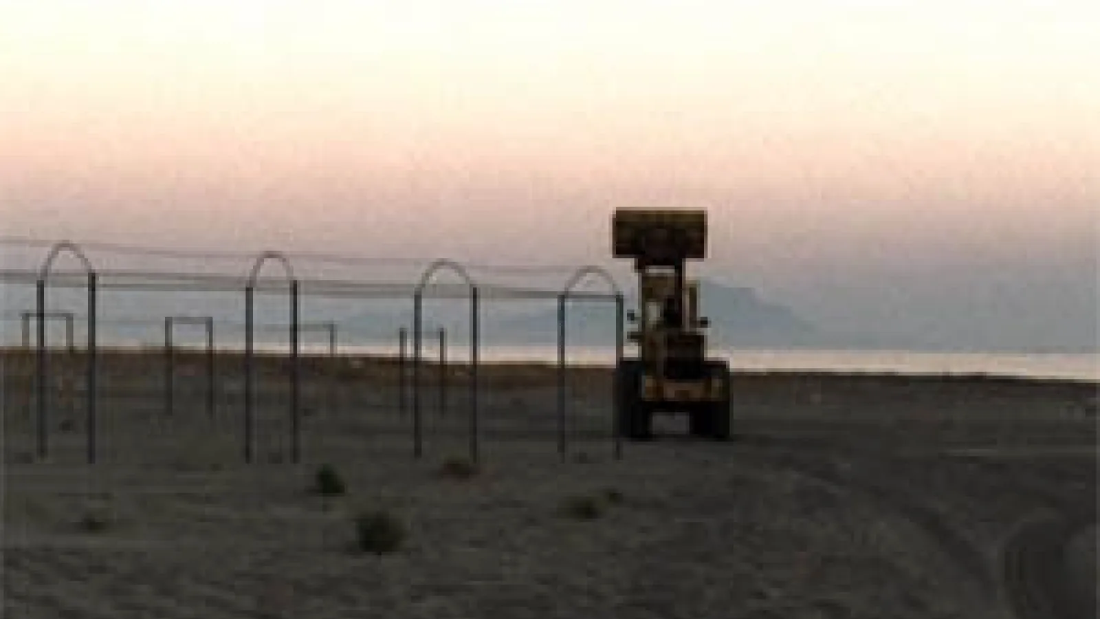a beach with metal playground equipment and a sand scooper machine