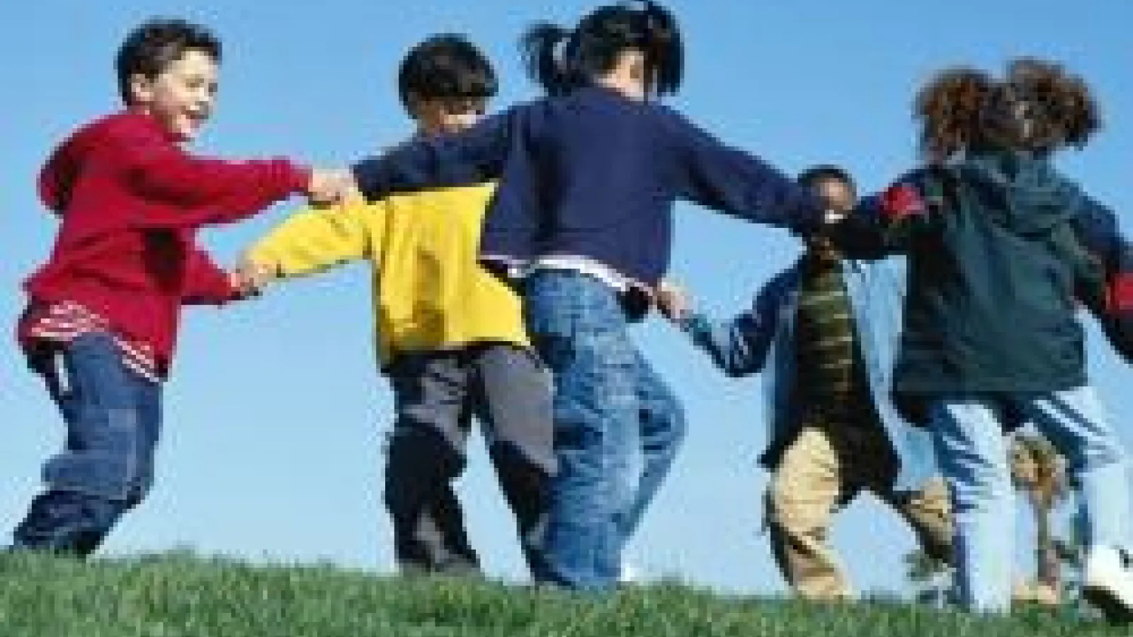 A group of children holding hands in a circle dancing