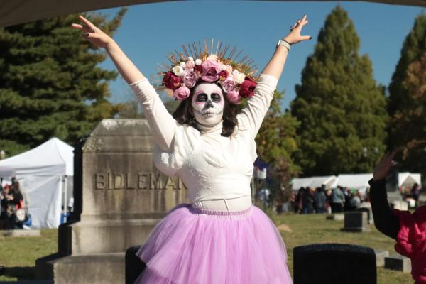 Woman in skeleton costume in front of gravestone