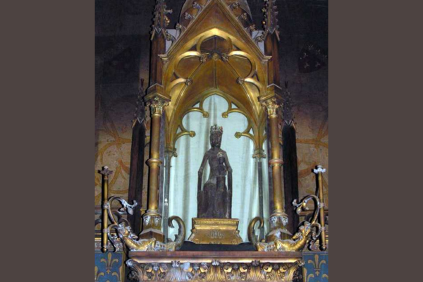 A religious statue of a black Madonna figure in a gold alter