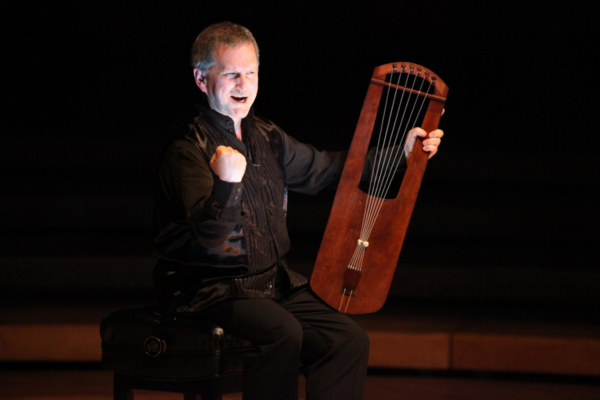 A man playing a dulcimer on a stage in the dark
