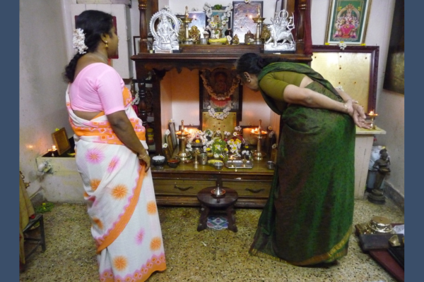 Two women stand before a street altar