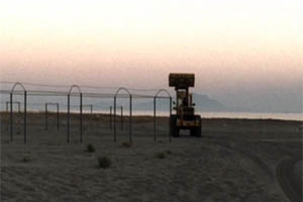 a beach with metal playground equipment and a sand scooper machine