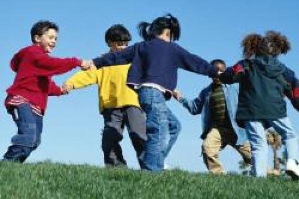A group of children holding hands in a circle dancing