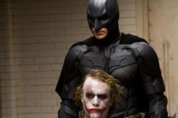 Image from a batman movie with batman standing behind joker